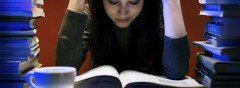 Student in a library surrounded by piles of books